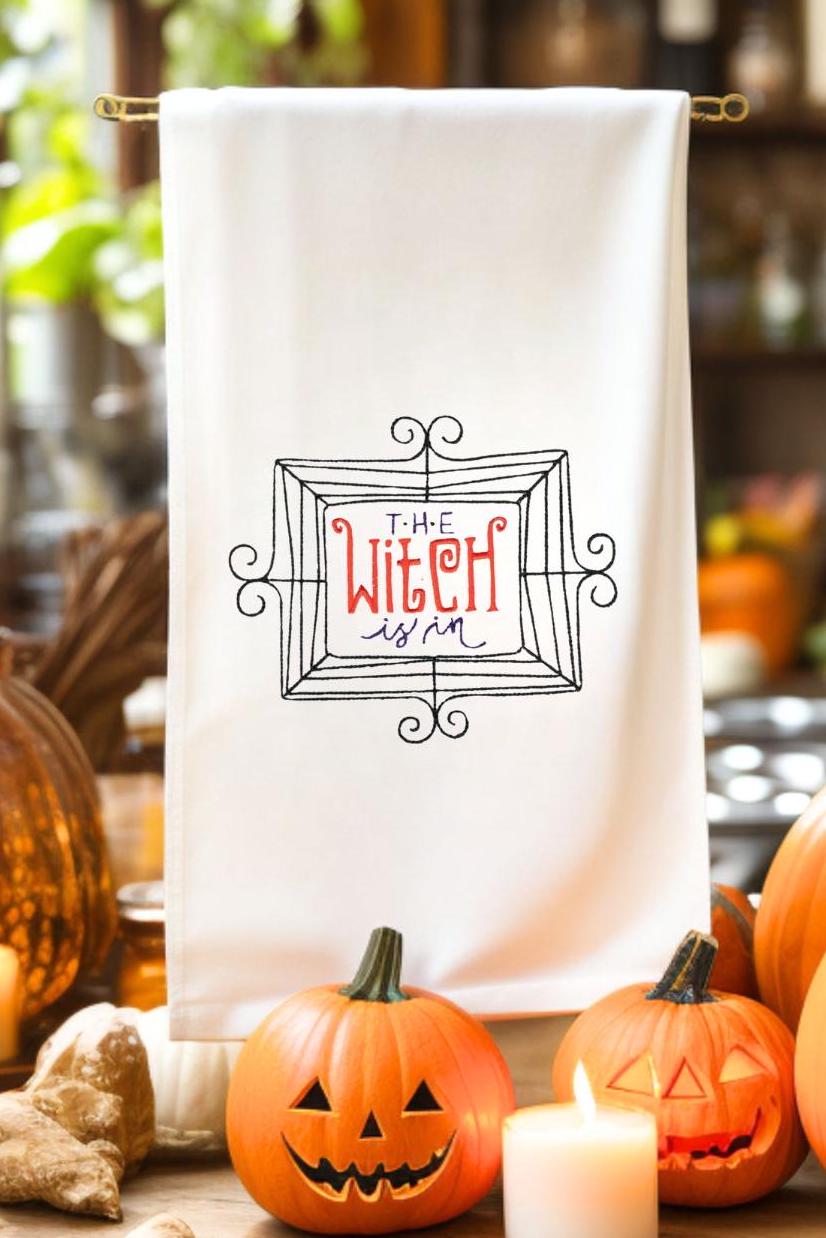 "The Witch is In" embroidered on a white tea towel. Sweet Humble Home HalloweenTea Towel surrounded by jack o lanterns