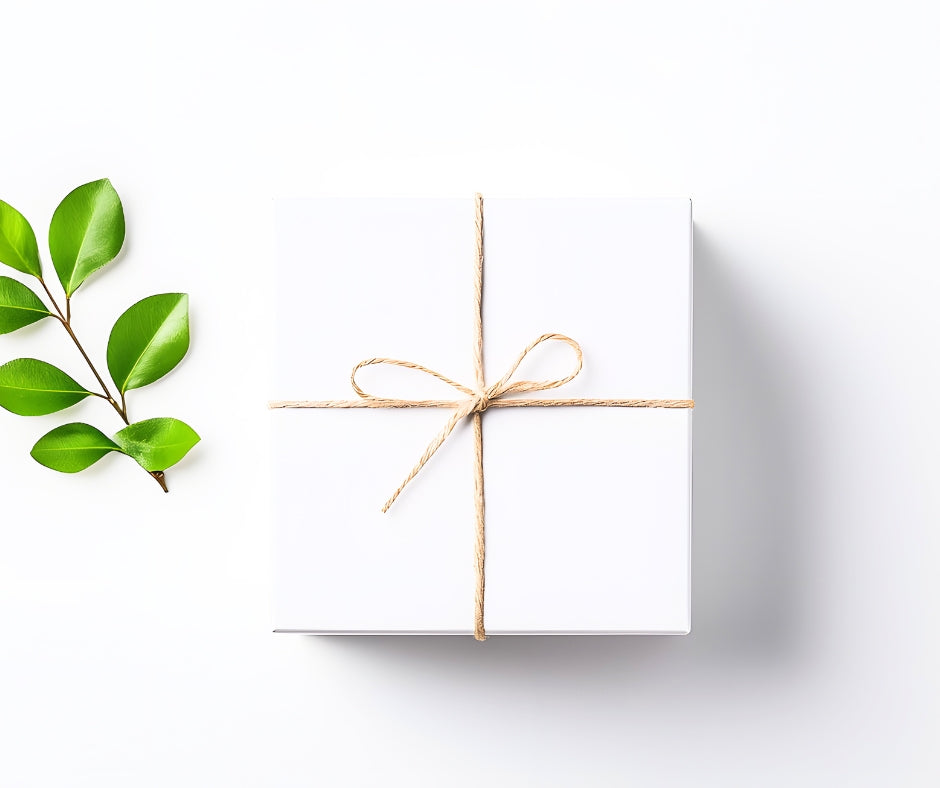 A simple white box wrapped in twine with a green branch to the left.