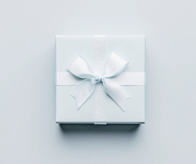 A small present in a light blue box with a white ribbon on a light blue background.
