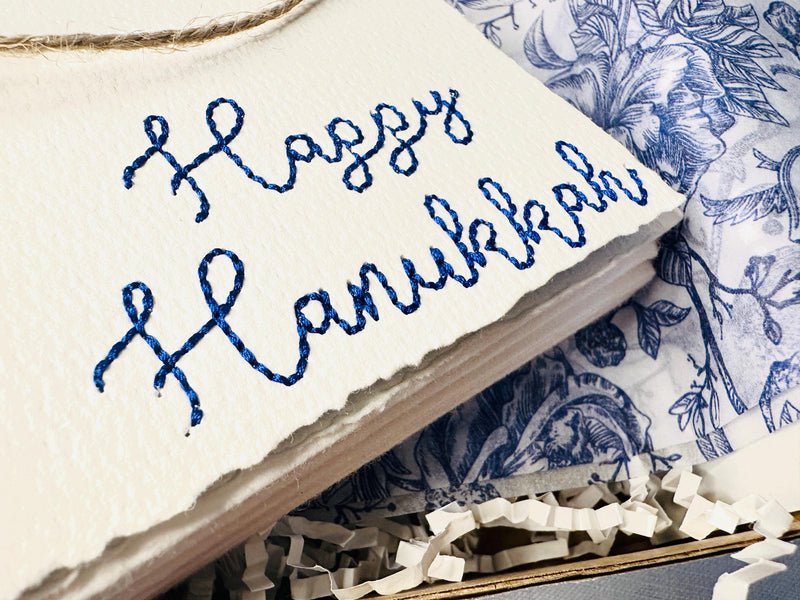 Happy Hanukkah Handmade Embroidered Greeting Card set embroidered in blue and set in a box for packaging with blue and white chinoiserie tissue paper.