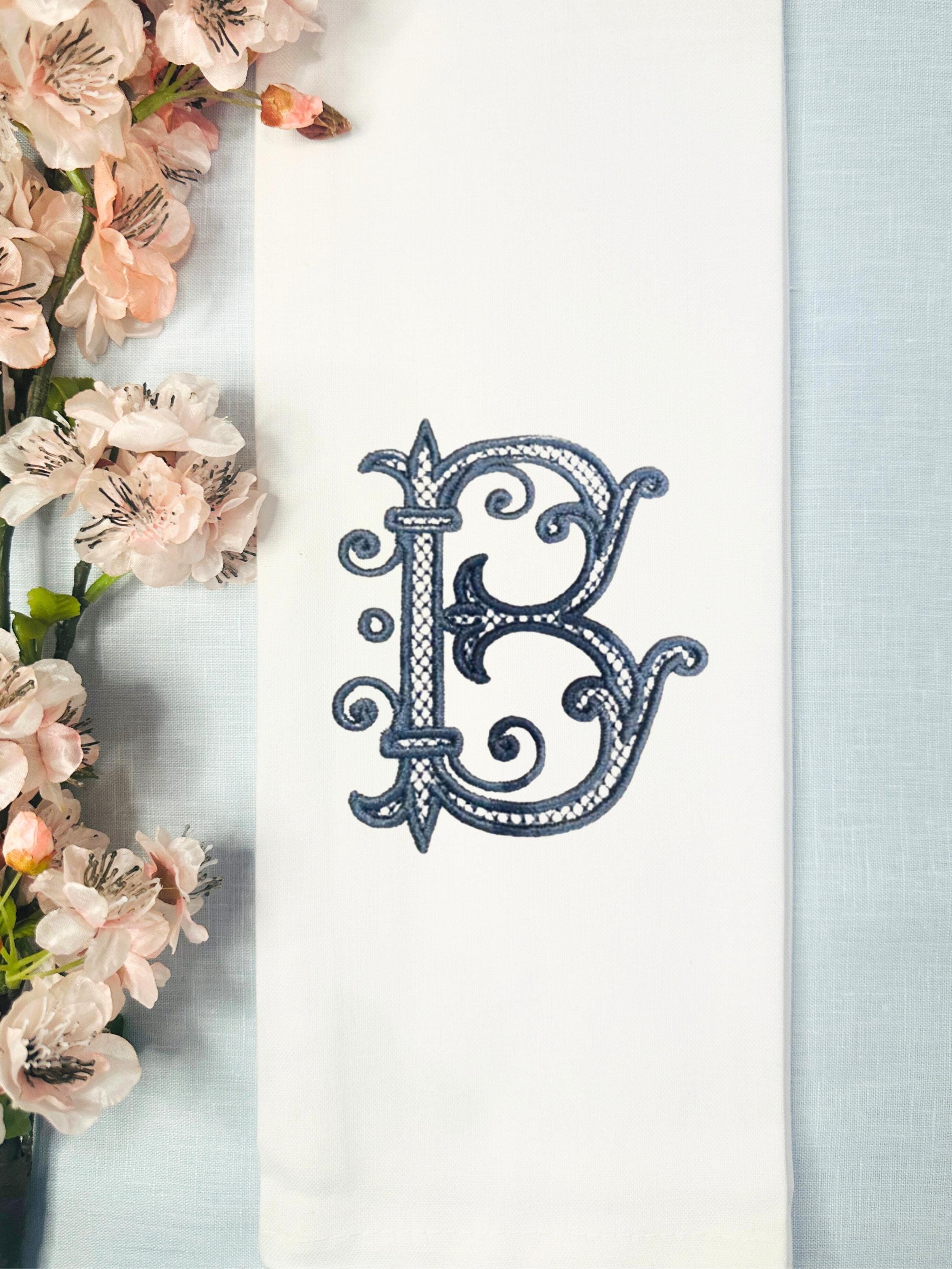 White tea towel with the Roman letter B embroidered in blue. Cherry blossoms to the left.