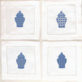 Set of four white linen napkins each with a slightly different chinoiserie design stitched in blue on each. They are set on a white background.