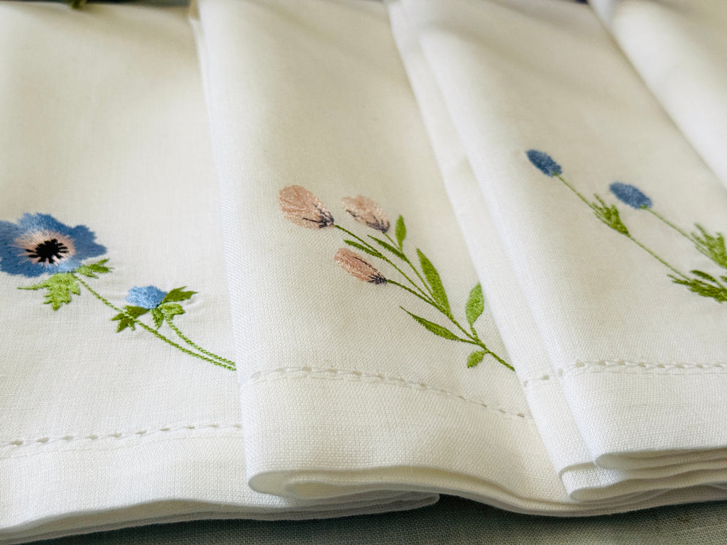 White linen/cotton fabric with embroidered wildflower floral designs on a neutral background.
