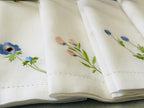 White linen/cotton fabric with embroidered wildflower floral designs on a neutral background.