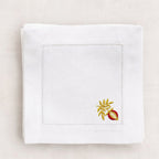 White napkin with embroidered design on a beige background