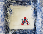 White embroidered cocktail napkin with red and blue USA in a decorative box with blue floral paper