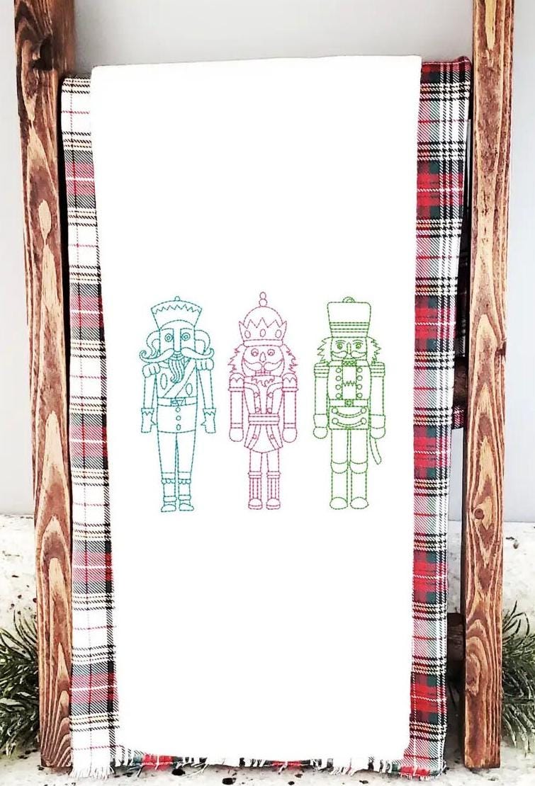 Three nutcrackers in simple stitch on a white tea towel set on a towel ladder on a counter for Teacher Appreciate Gift
