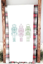 Three nutcrackers in simple stitch on a white tea towel set on a towel ladder on a counter for Teacher Appreciate Gift