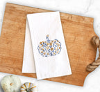 Autumnal home decor of a blue and golden orange Embroidered Pumpkin, on top of a cutting board with a rope handle and pumpkins to the lower left  used for Fall Hosting Decor, Thanksgiving Towel, Hostess Gifts, for Your Best Friend.