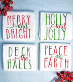 Set of 4 tea towels folded and on a light blue linen tablecloth with red berry branches. Gift for mom in red and green.