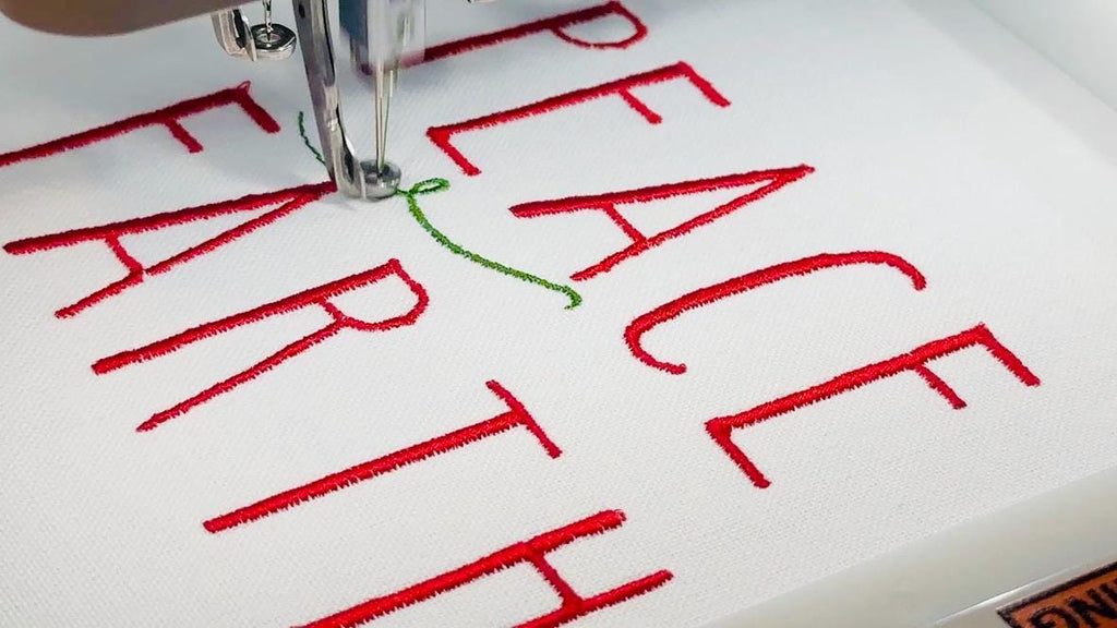 Close up shot of the Peace on Earth tea towel being embroidered in red and green.