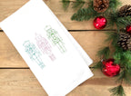 Three nutcrackers in simple stitch on a white tea towel set on wooden table with Christmas greens and red balls.