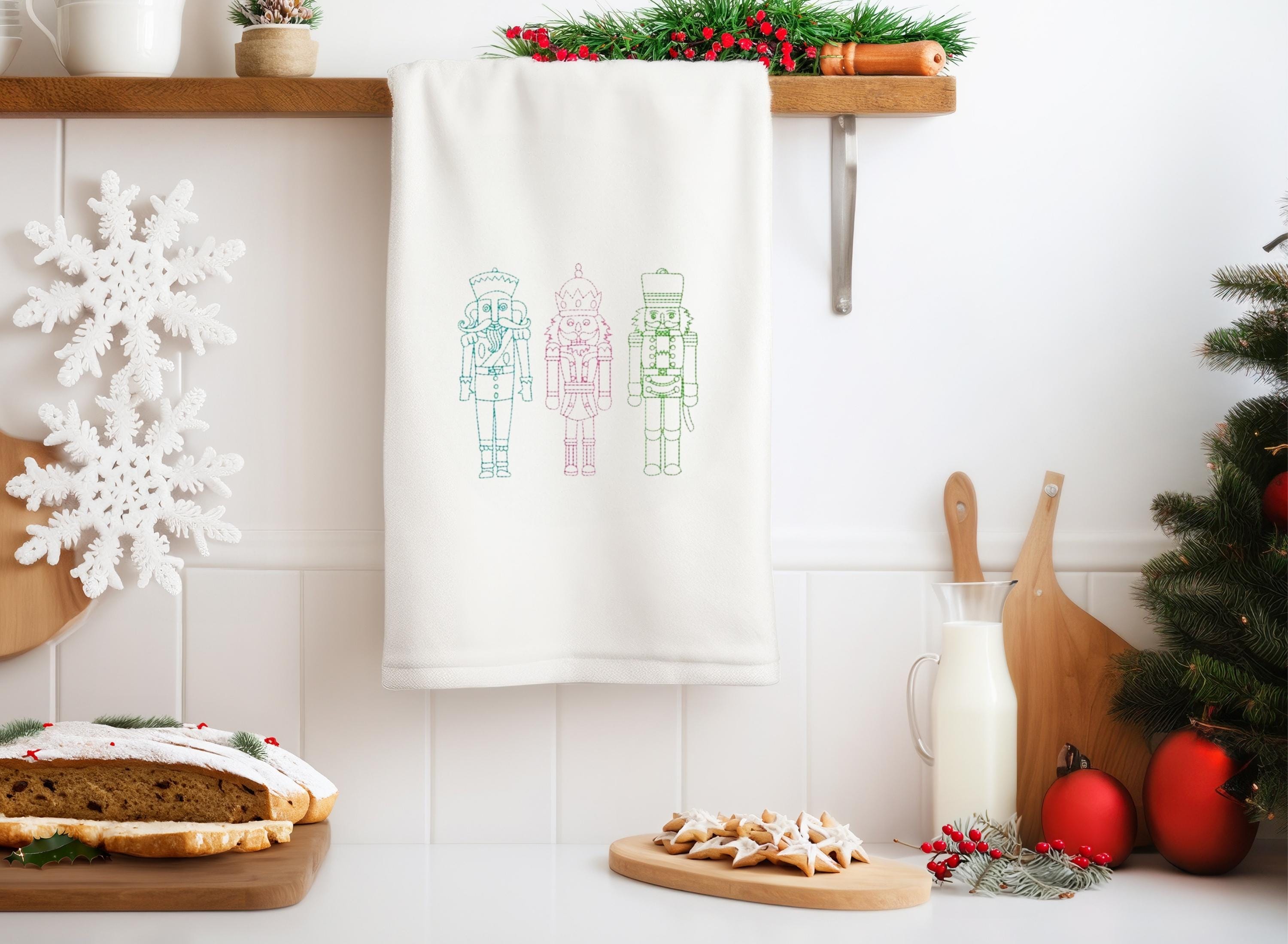 Three nutcrackers in simple stitch on a white tea towel set on a towel ladder on a counter for Teacher Appreciate Gift in a very festive kitchen.