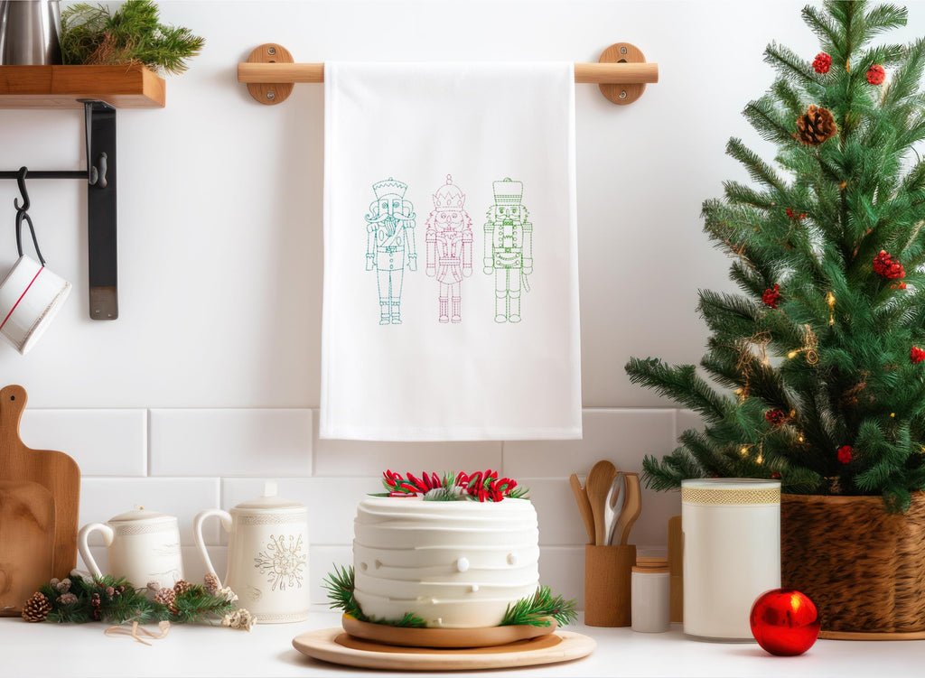 Three nutcrackers in paster blue, pink, and green set on a white towel hanging in a festive kitchen.